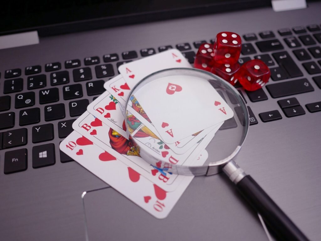Playing cards, dice and a magnifying glass resting on a laptop keyboard