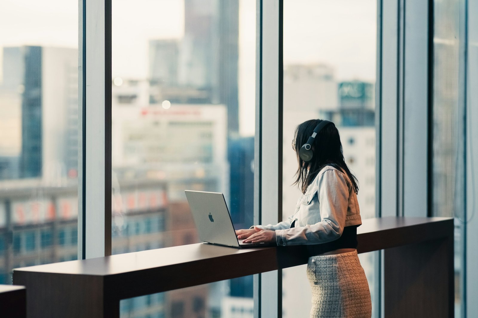 A professional working at a laptop by an office window overlooking the city